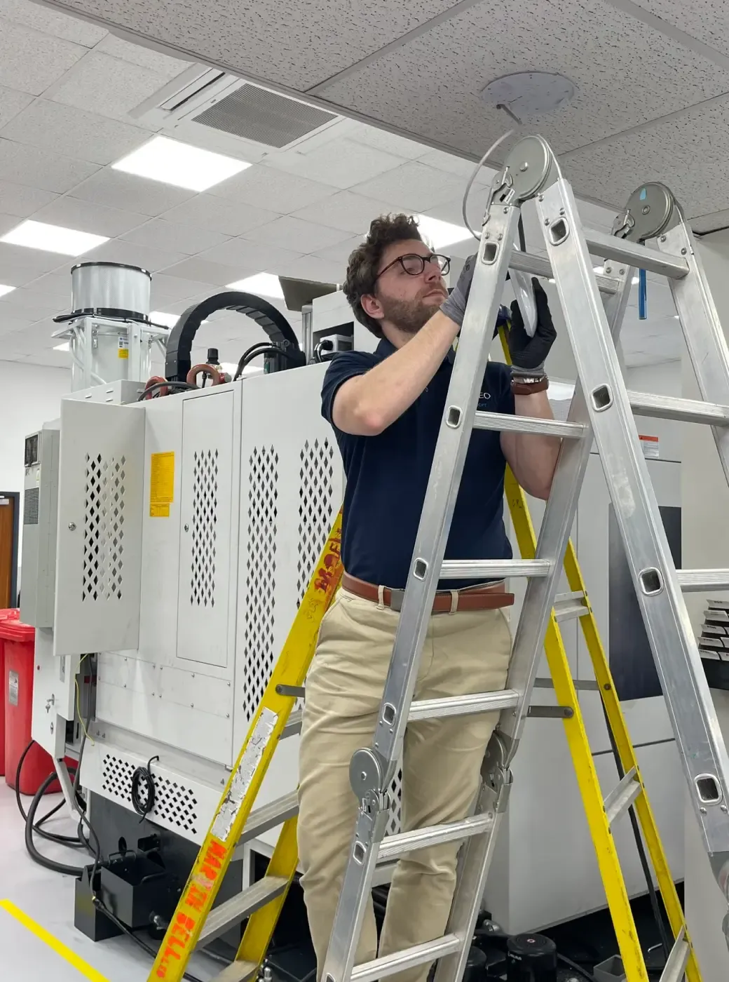 VISCREO employee on ladder installing Ubiquiti access point on ceiling